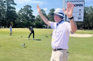 A volunteer at the 13th tee box at Pinehurst signals to the crowd to stay silent as UF sophomore Parker Bell tees off.